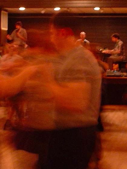 A blur of contra dancers, with band in the background