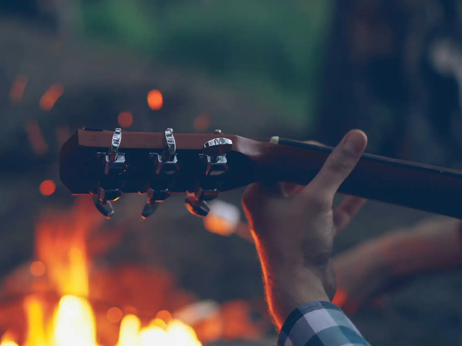 A person plays guitar by a campfire. Photo by Vitaly Gariev on Unsplash.