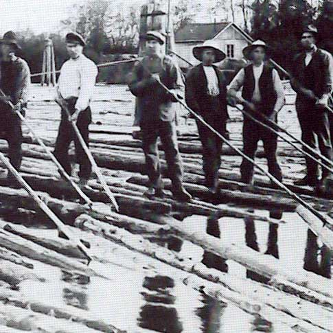 Antique photograph of log drivers standing on floating logs