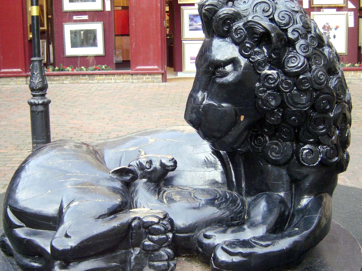 Sculpture of a lion lying down with a lamb