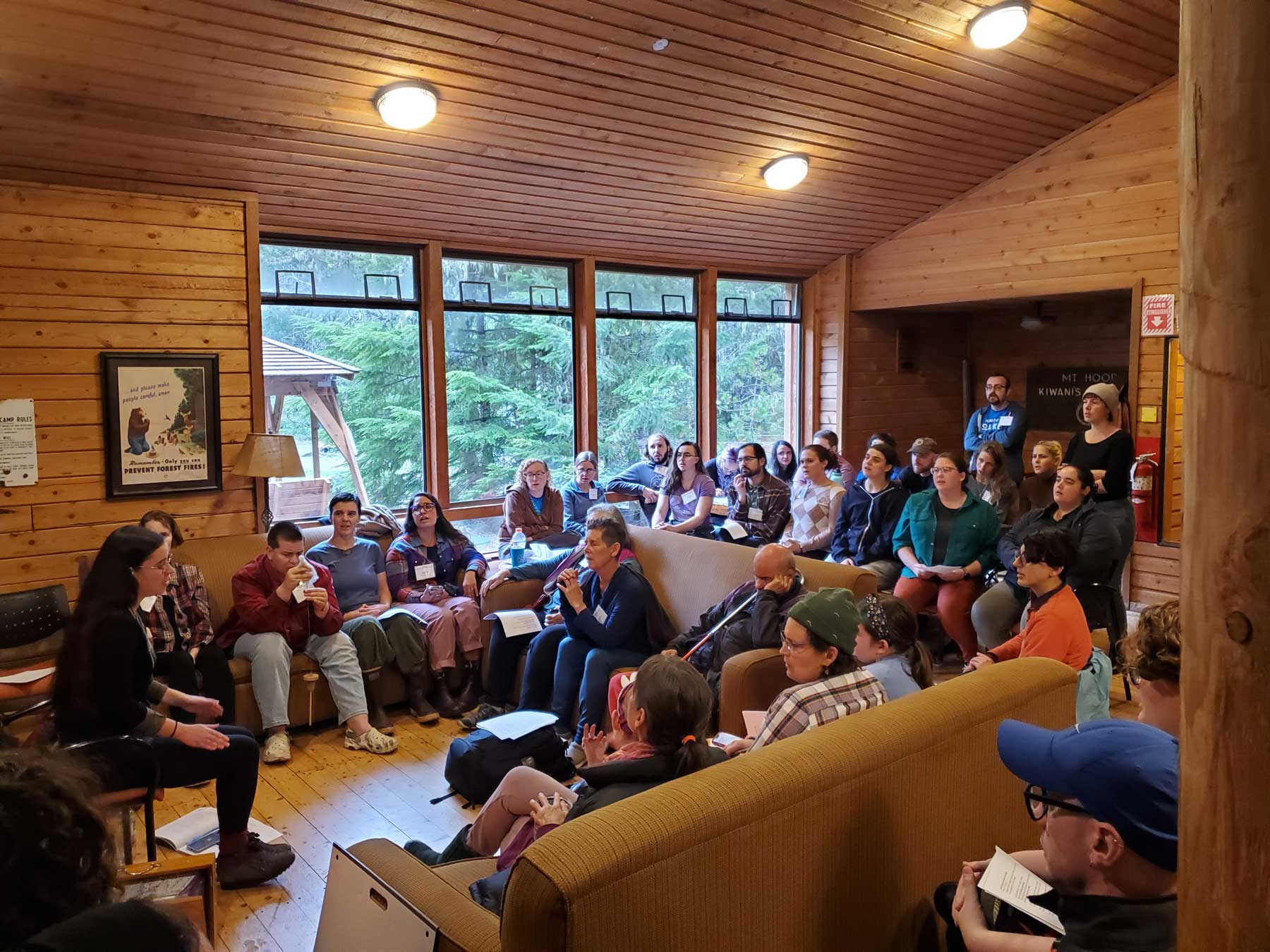 Participants singing in a room with a forest view at Raise the Rafters in Oregon
