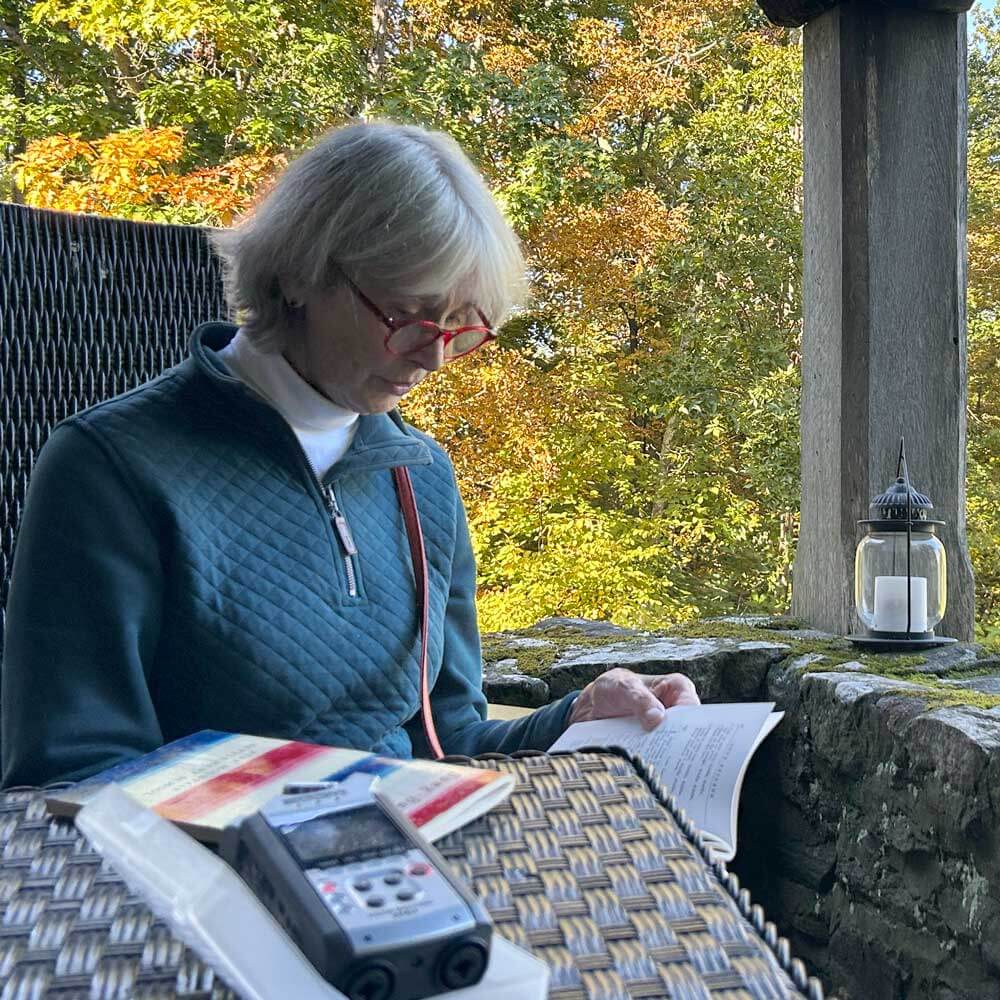 Roxana Robinson sits on a stone porch in an autumn landscape