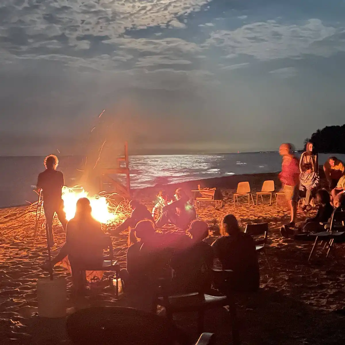 Campers around a campfire by a moonlit lake. Photo by Howard Carlberg.