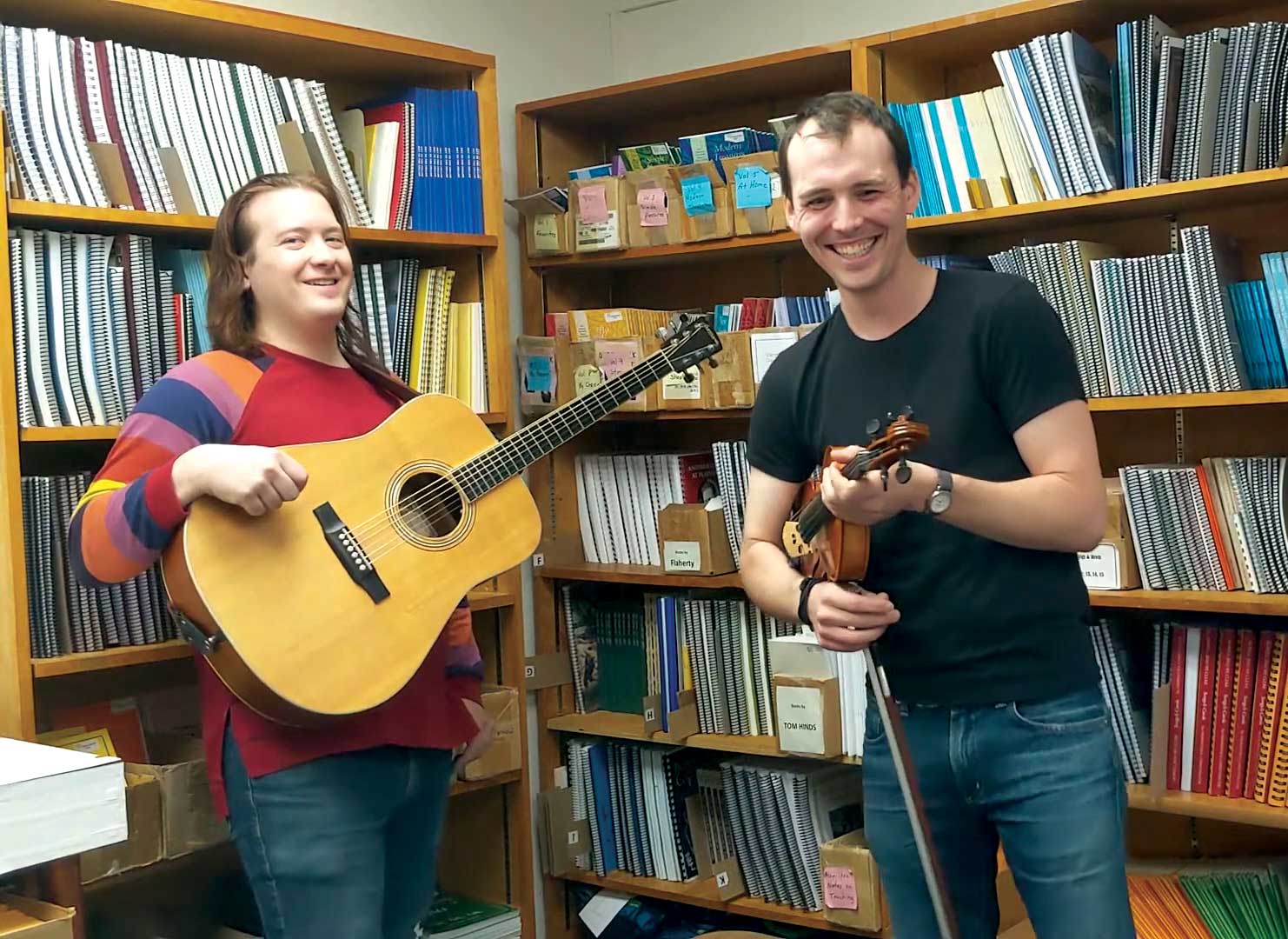 Brian Lindsay and Alex Sturbaum playing guitar and fiddle in the CDSS store room